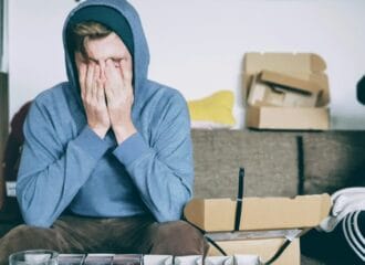 man covering face with both hands while sitting on bench