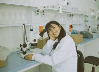 woman in white laboratory gown holding black instrument