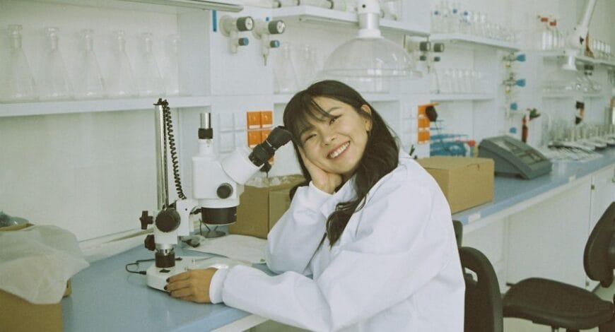 woman in white laboratory gown holding black instrument