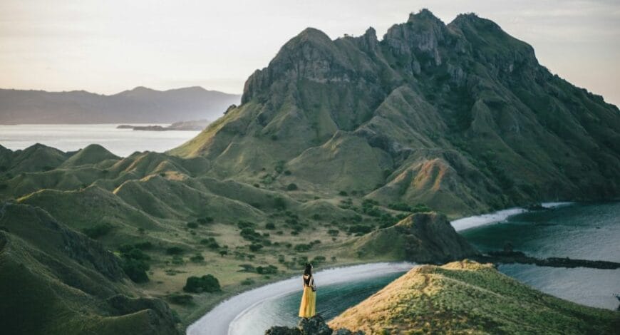 woman standing on mountain near body of water