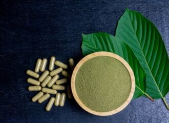 kratom powder in a bowl next to pills