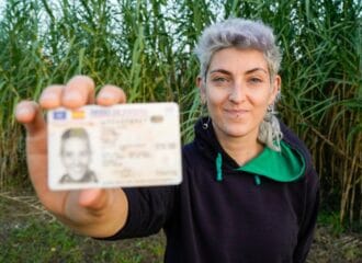 woman holding her license in a field
