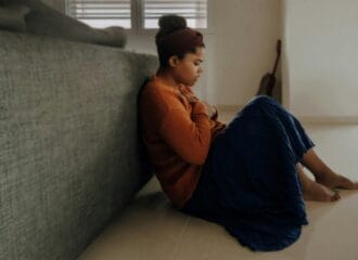 woman in orange sleeve shirt sitting near gray couch