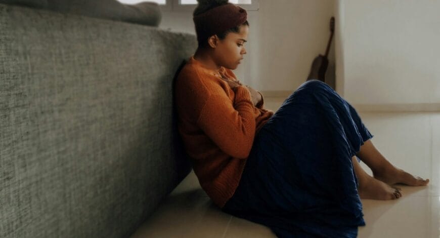 woman in orange sleeve shirt sitting near gray couch