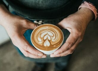 hands holding an espresso latte