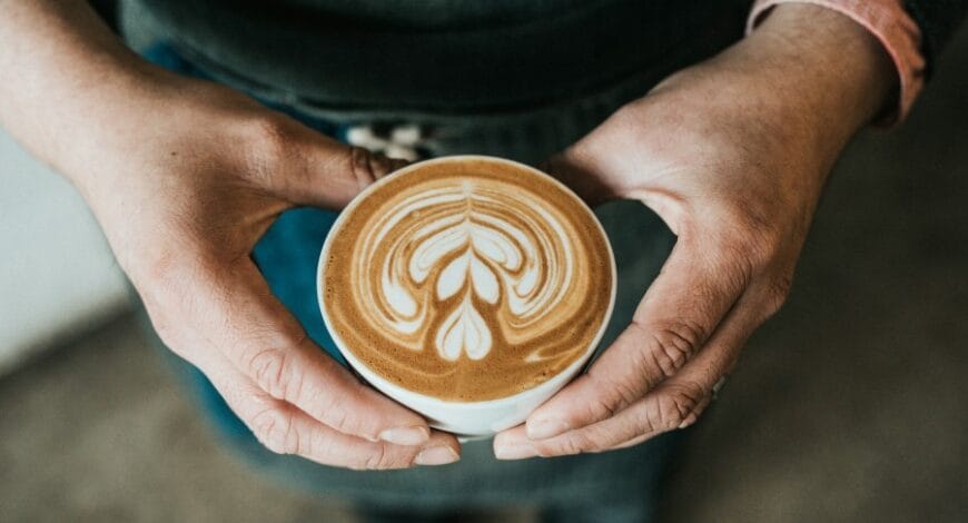 hands holding an espresso latte