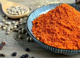 A bowl of powdered spices next to a wooden spoon