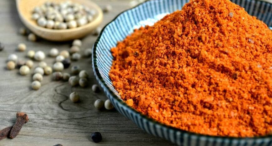 A bowl of powdered spices next to a wooden spoon