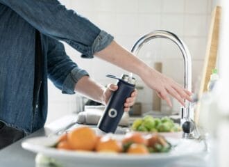 A person filling a water bottle at a sink