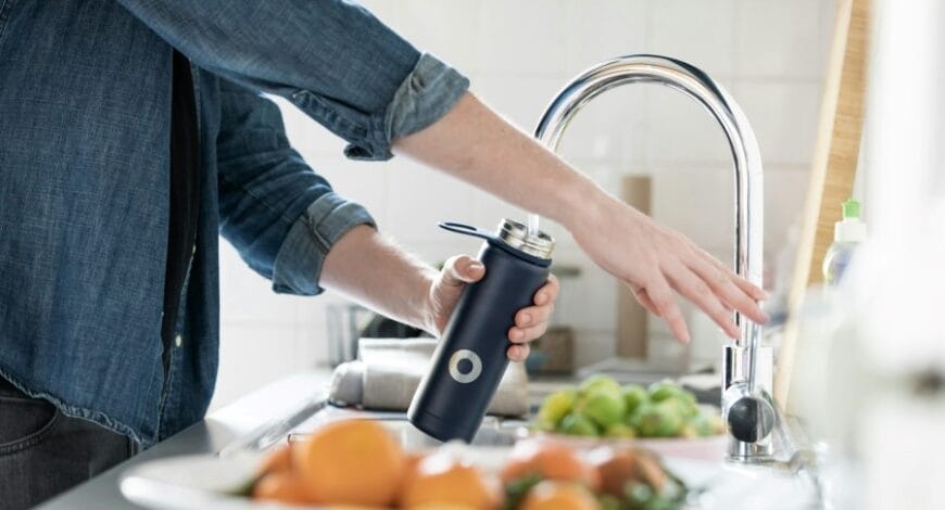 A person filling a water bottle at a sink
